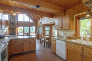 Une cuisine spacieuse avec des meubles en bois, un grand îlot central et une cheminée en pierre.