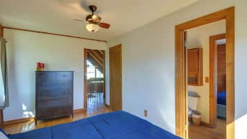 A bedroom with a bed, dresser, ceiling fan, and wooden doorways leading to other rooms.