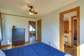 Ein Schlafzimmer mit einem Bett, einem Schminktisch, einem Deckenventilator und Holztüren zu anderen Räumen.