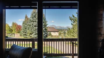 A room with a view of a mountain range through a window.