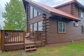 Eine Blockhütte mit Veranda, einer Terrasse und einem großen Fenster.