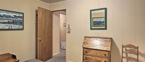 A bedroom with a bed, a wooden dresser, a chair, and two framed pictures on the wall.