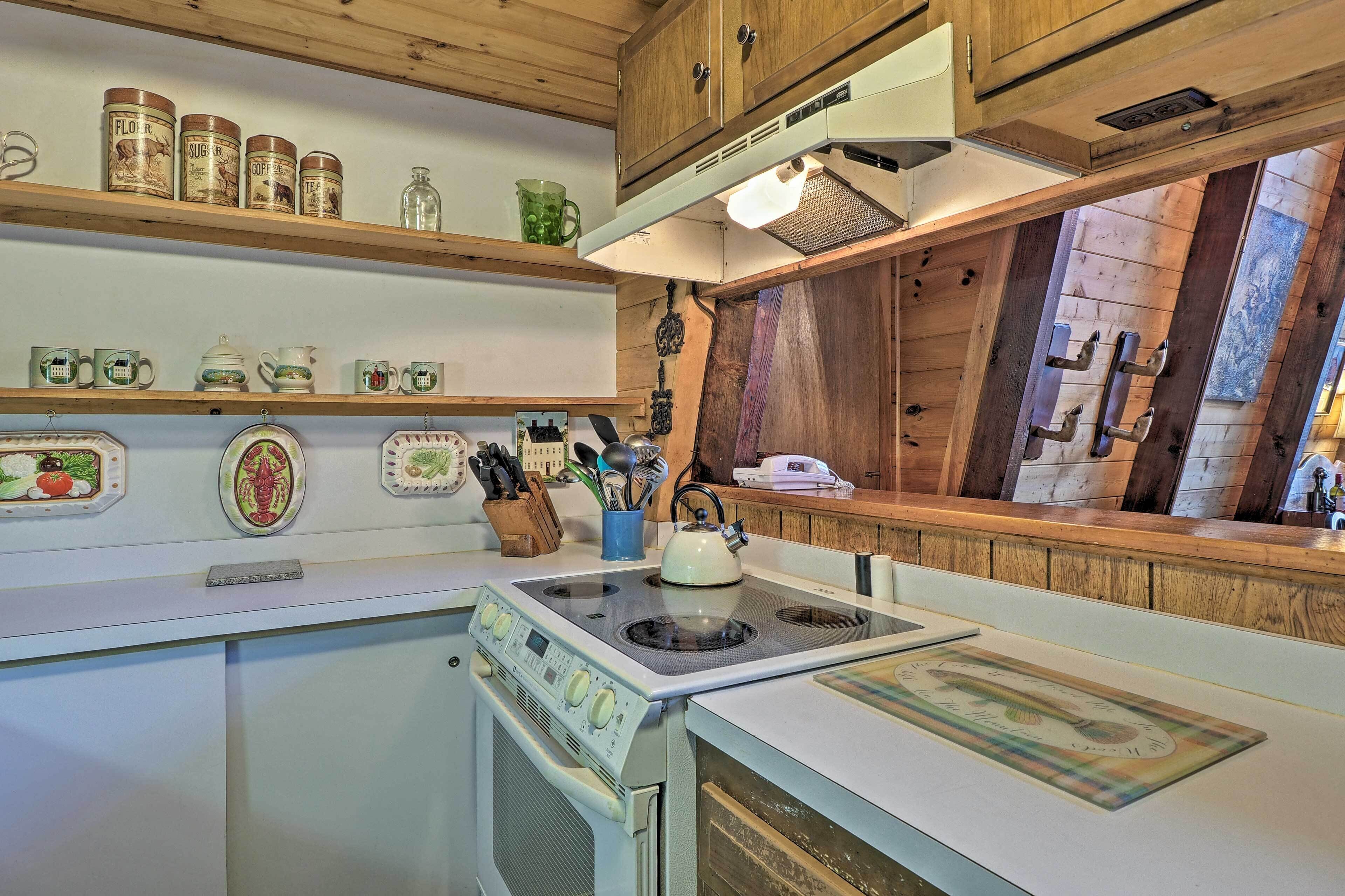 Una cocina con armarios de madera, una estufa y diferentes utensilios.