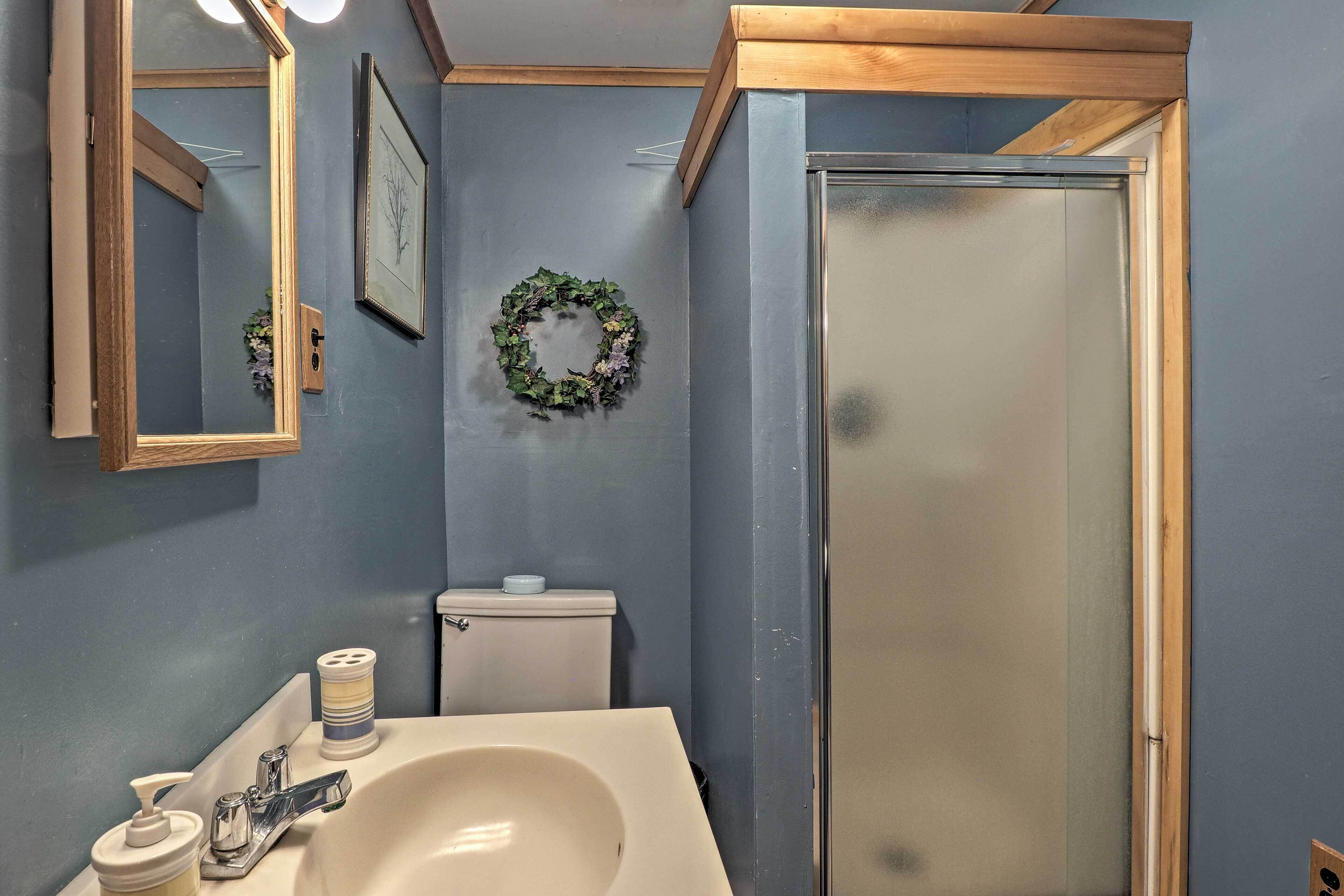 A bathroom with a white sink, a mirror, a toilet, and a shower.