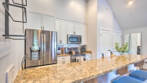 A modern kitchen with white cabinets, stainless steel appliances, a granite countertop, and blue bar stools. - 5 Mi to Ski Resort: Breck Penthouse Studio (Breckenridge)