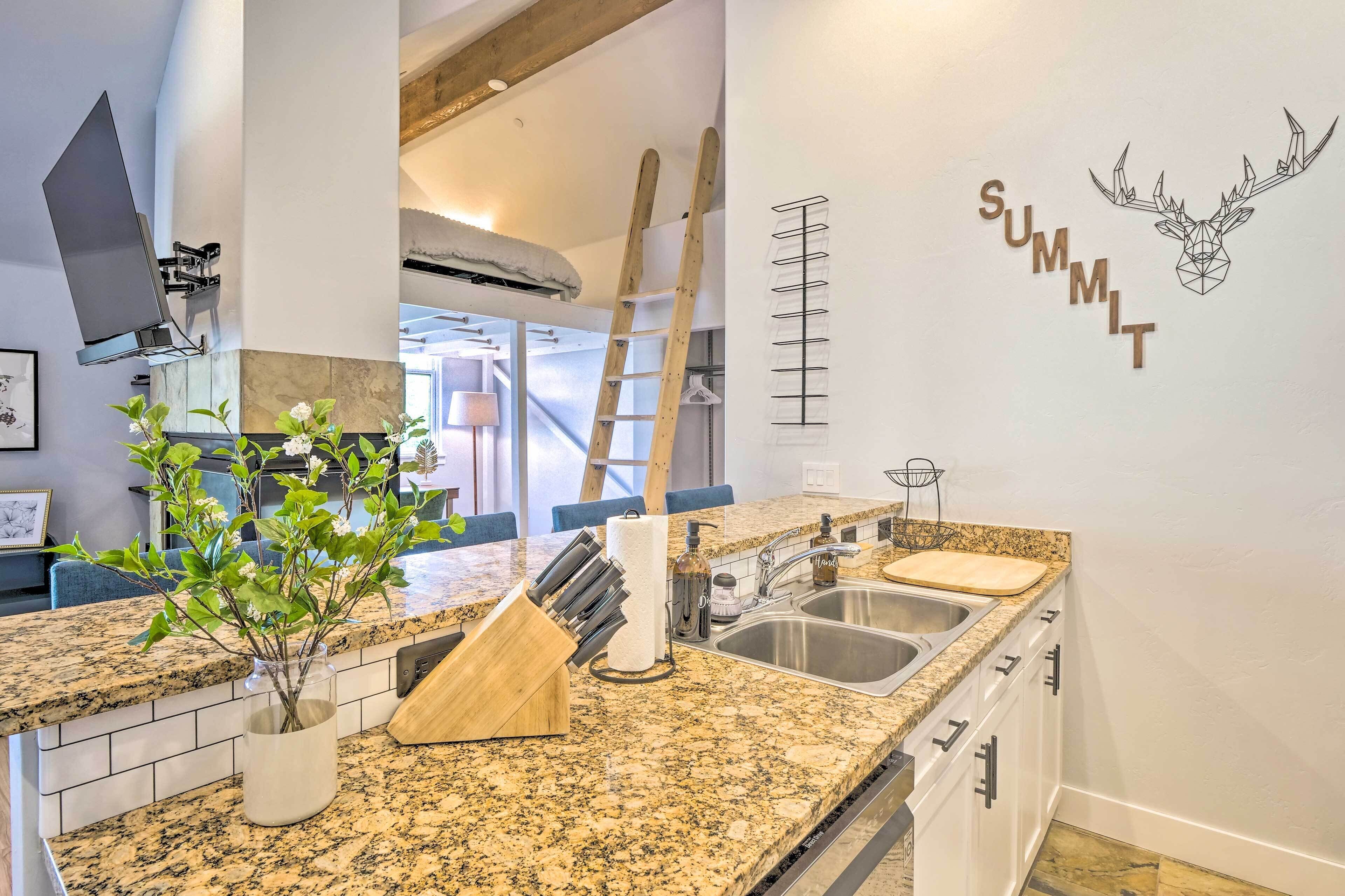 Una cucina moderna con piani in granito, un supporto in legno per piante, un blocco portacoltelli e un porta asciugamani a parete.