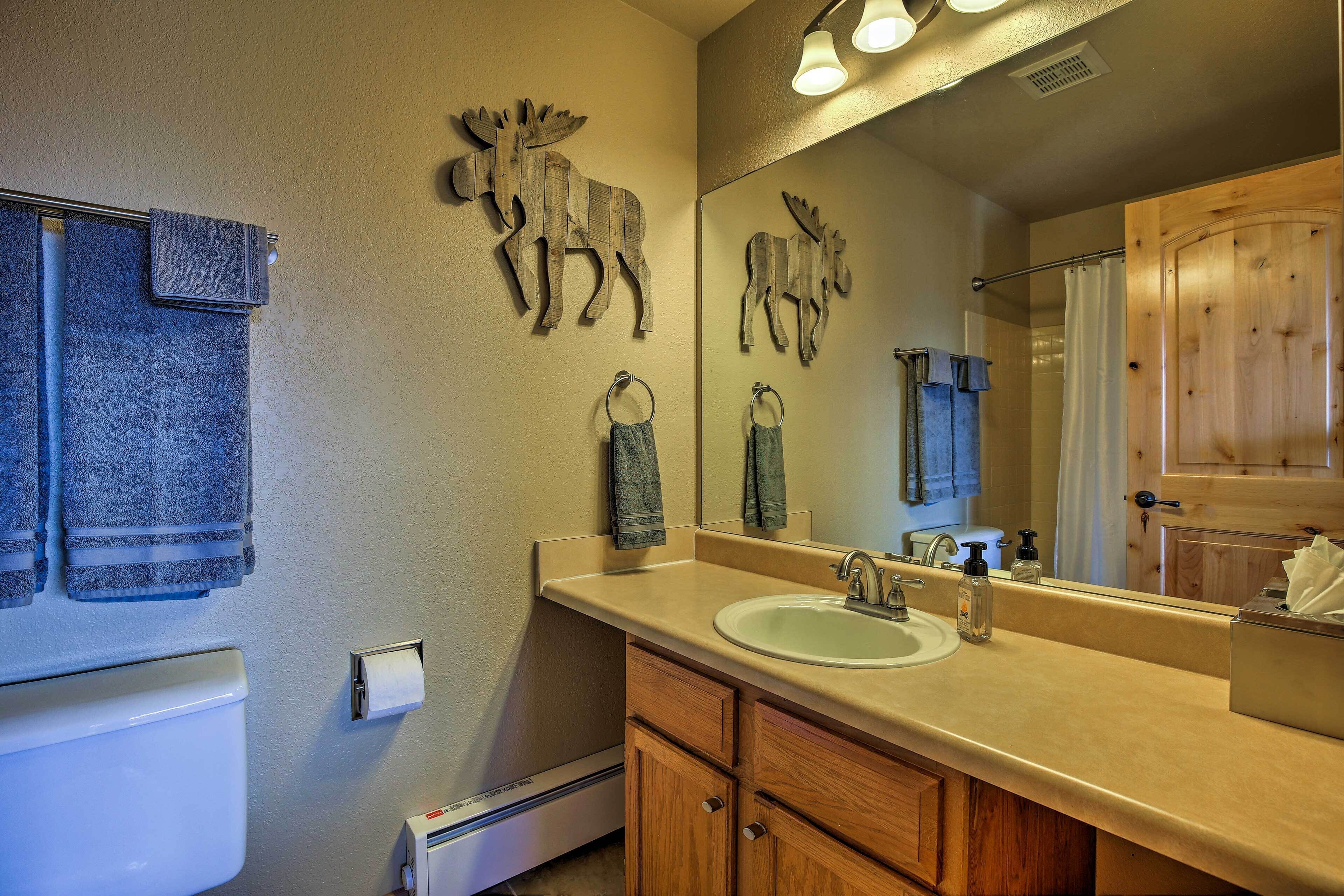 A bathroom with a wooden vanity, a sink, a mirror, and two moose wall decorations.