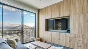 A modern living room with a large window, a sofa, a coffee table, and wooden cabinetry.