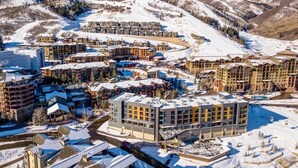 A snow-covered resort with multiple buildings, ski slopes, and a clear sky.