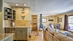 A kitchen with a built-in dishwasher, a wooden door, and a dining area with a table and chairs. - Spacious Grand Lake Cabin w/ Hot Tub & Deck (Grand Lake)