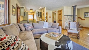 A cozy living room with a sectional sofa, a round coffee table, and a fireplace. - Spacious Grand Lake Cabin w/ Hot Tub & Deck (Grand Lake)