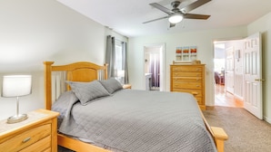 A bedroom with a bed, nightstands, a dresser, a ceiling fan, and a door leading to another room. - Watts Bar Lake Escape: Private Boat Dock + Ramp! (Spring City)