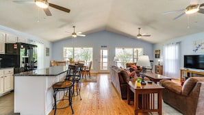 A spacious living area with a kitchen, dining area, and a large window. - Watts Bar Lake Escape: Private Boat Dock + Ramp! (Spring City)