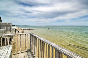 Eine Holzsteg führt zu einem ruhigen Meer unter einem bewölkten Himmel.