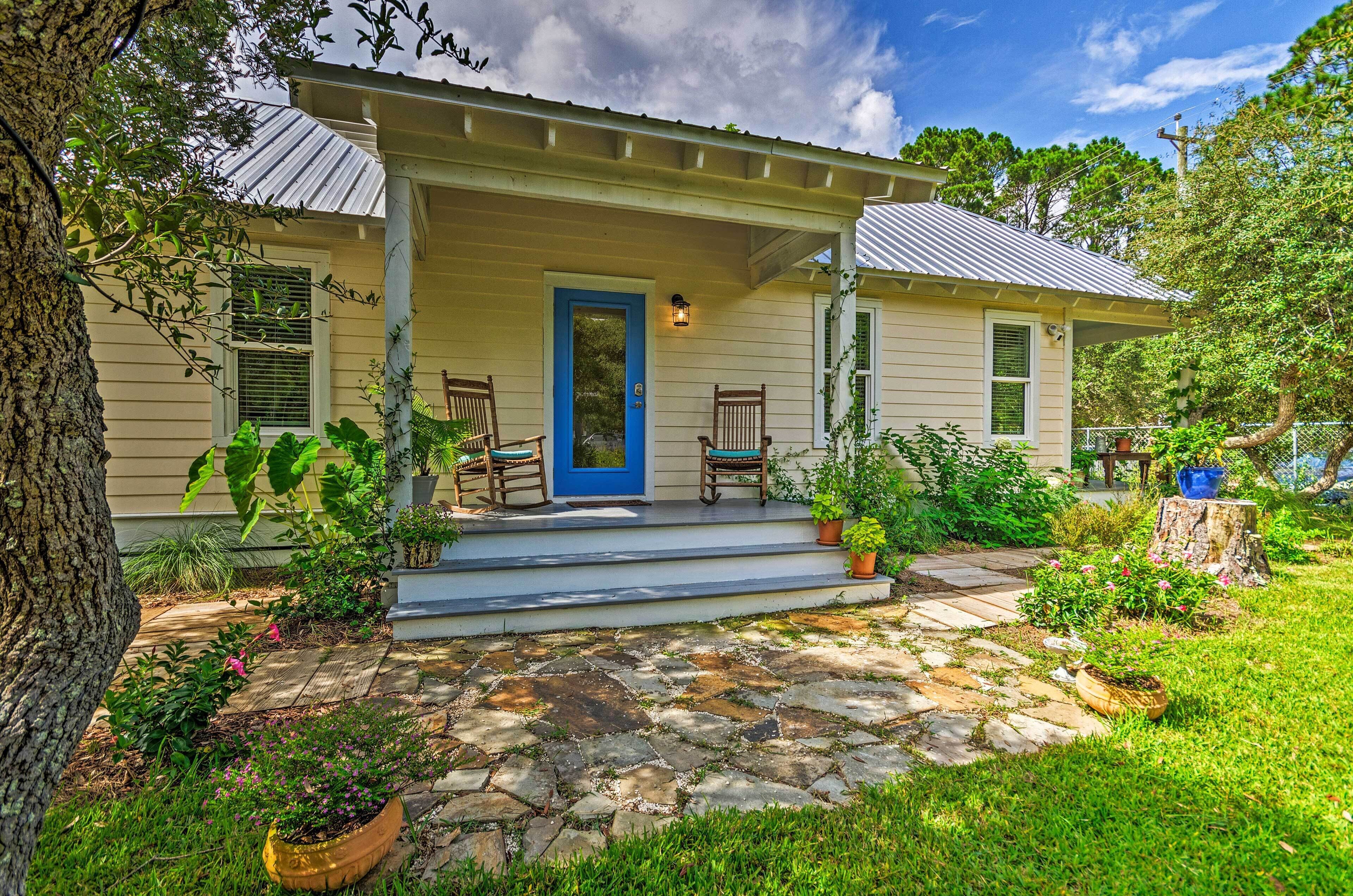 A house with a porch, stone pathway, and potted plants.