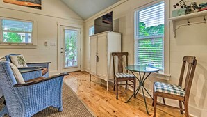 A room with a wooden floor, a blue wicker sofa, a dining table with chairs, and a refrigerator. - Seagrove Beach Studio - 1/4 Mi to Beach Access! (Santa Rosa Beach)