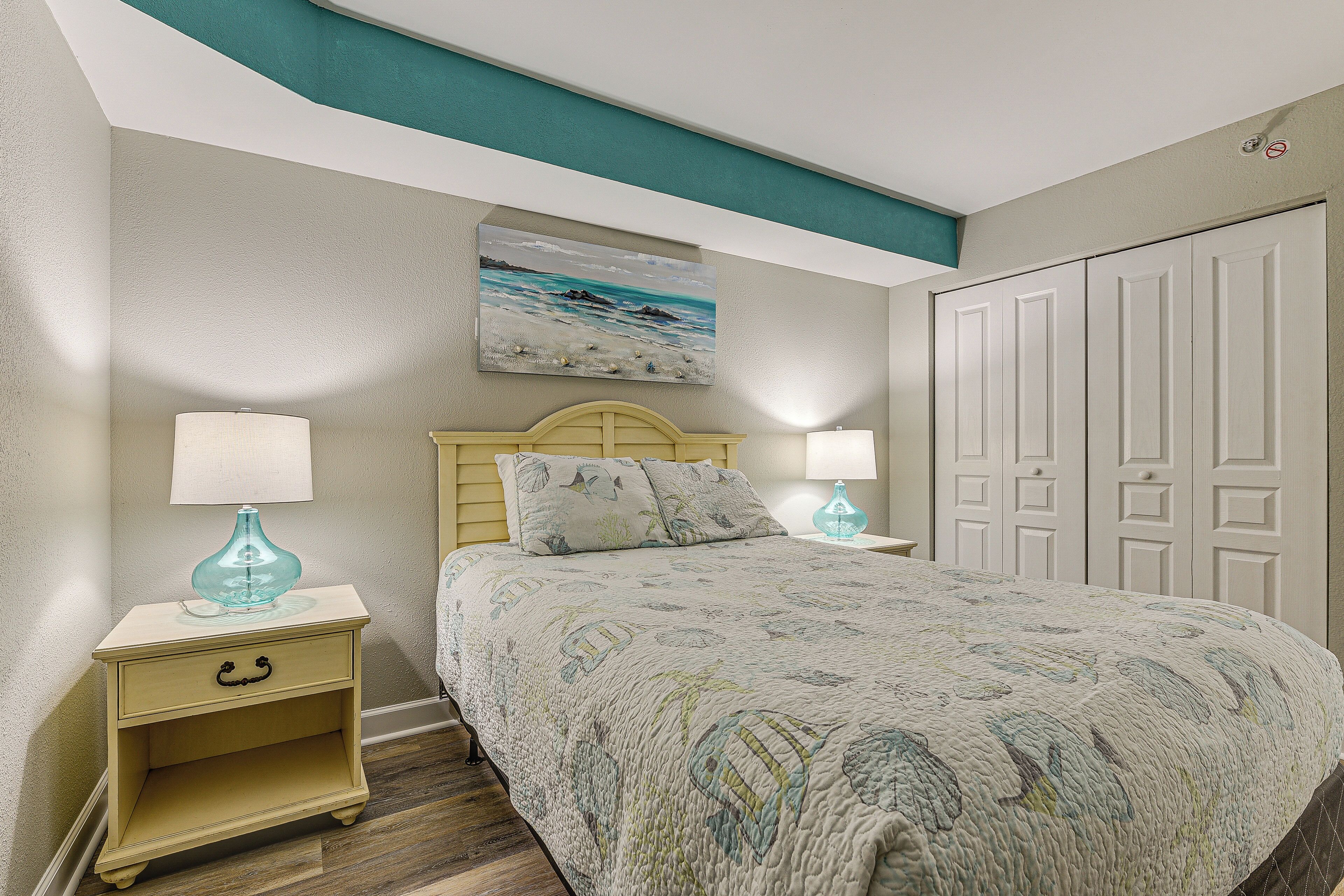 A bedroom with a bed, nightstands, a painting, and a wardrobe.