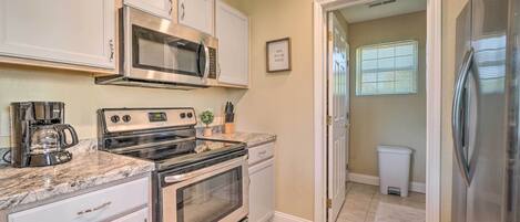 A kitchen with a stainless steel refrigerator, a built-in microwave, a stove, and a coffee maker.