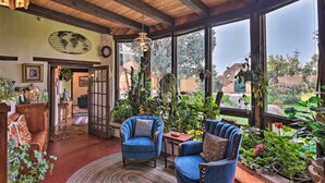 A cozy room with wooden beams, large windows, and a variety of plants. - Riverheart Retreat - One-of-a-kind Villa! (Buena Vista)