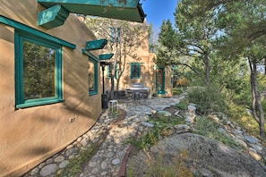 Un bâtiment de style rustique, avec un chemin de pierre menant à un patio aménagé avec du mobilier d’extérieur.