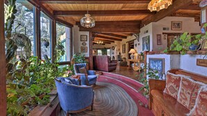 A spacious living room with wooden beams, large windows, and various plants. - Riverheart Retreat - One-of-a-kind Villa! (Buena Vista)