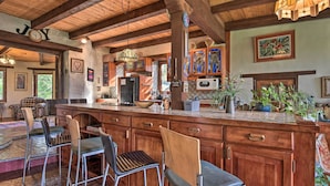 A spacious kitchen with wooden cabinets, a large island with bar stools, and a chandelier. - Riverheart Retreat - One-of-a-kind Villa! (Buena Vista)