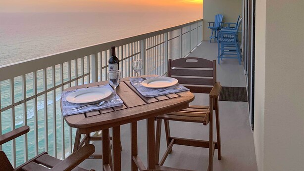 Un balcón con una mesa dispuesta para dos personas, con vista al mar.