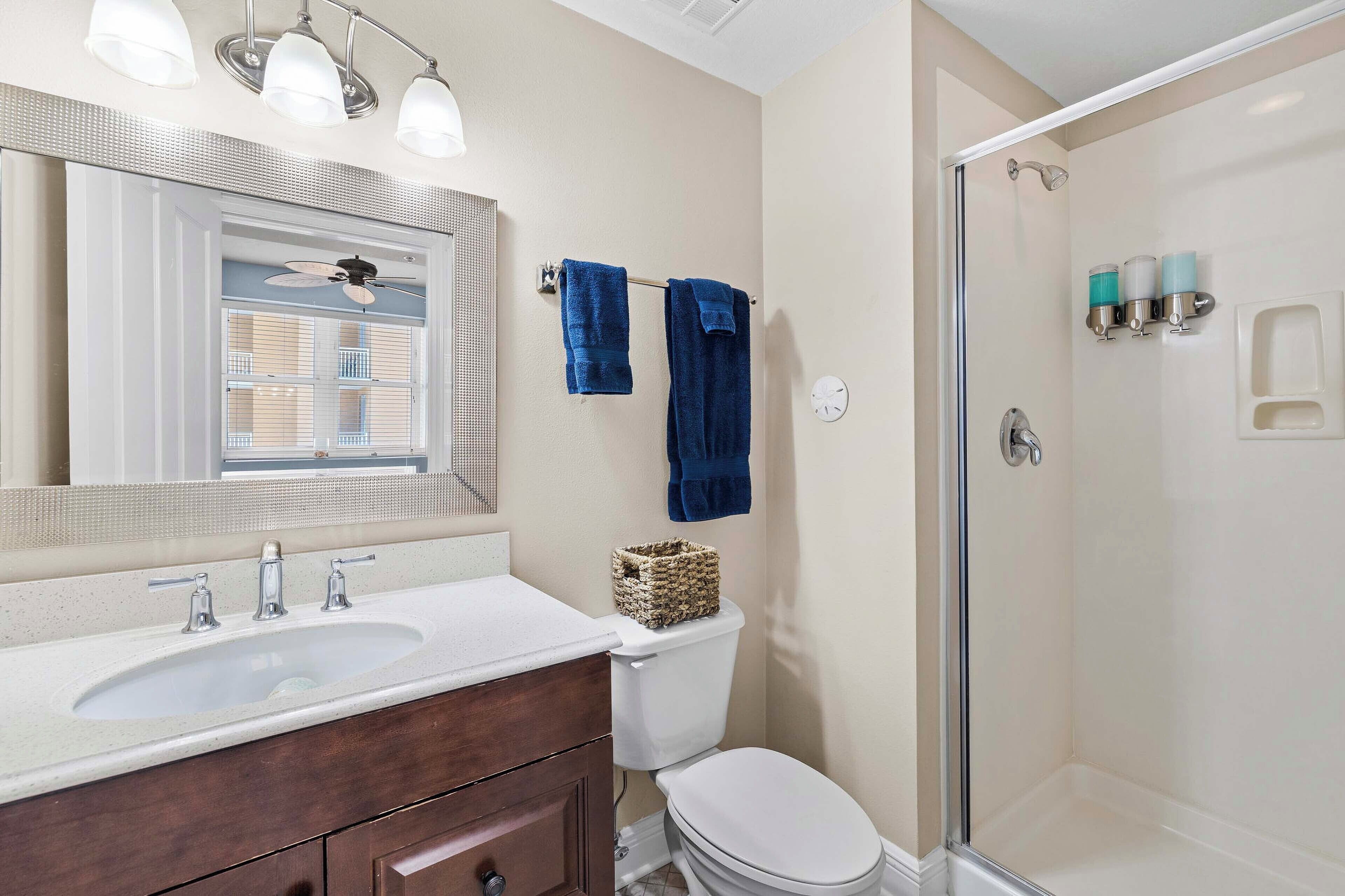 A bathroom with a white sink, a mirror, a toilet, and a shower area.