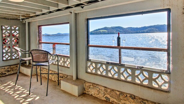 A room with large windows overlooking a body of water, a chair, and a bottle of wine. - Lakefront Retreat w/ Dock, Paddle Boards & Kayaks! (Clearlake)