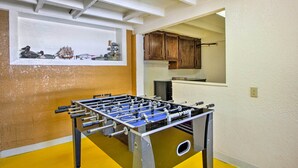 A room with a foosball table, a window with a view of a kitchen, and a shelf with decorative items. - Lakefront Retreat w/ Dock, Paddle Boards & Kayaks! (Clearlake)