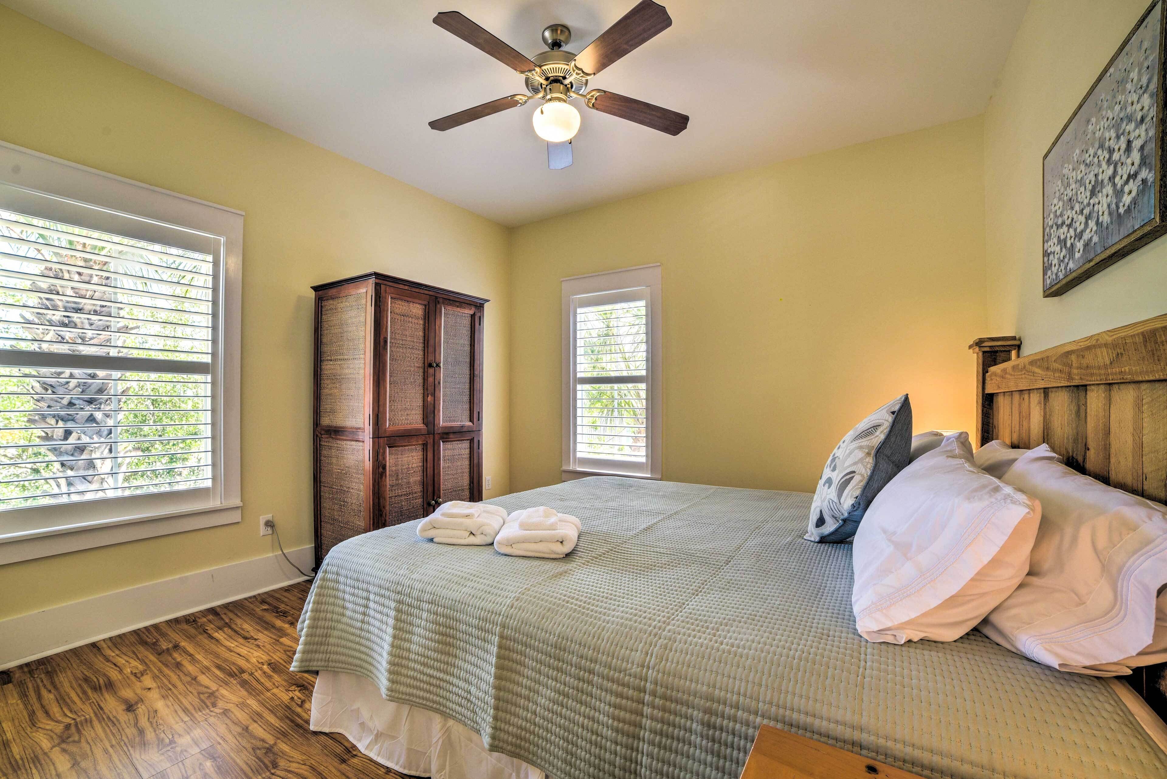 A bedroom with a bed, a ceiling fan, and a window.