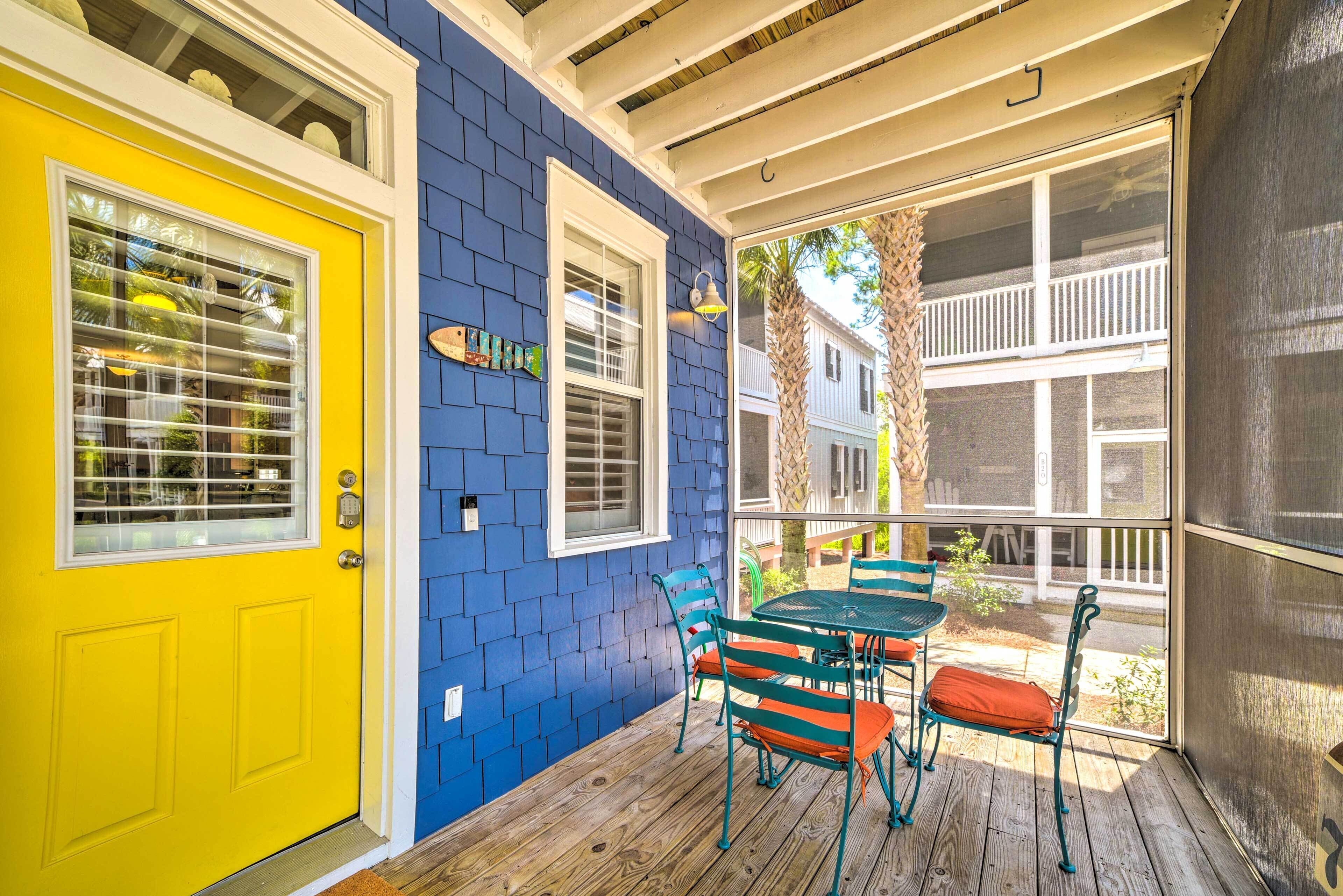 A porch with a yellow door, blue siding, and a screened area with a table and chairs.