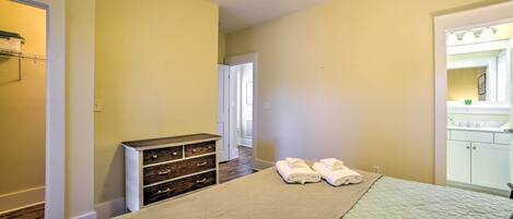 A bedroom with a bed, a dresser, a ceiling fan, and a bathroom visible through an open door.