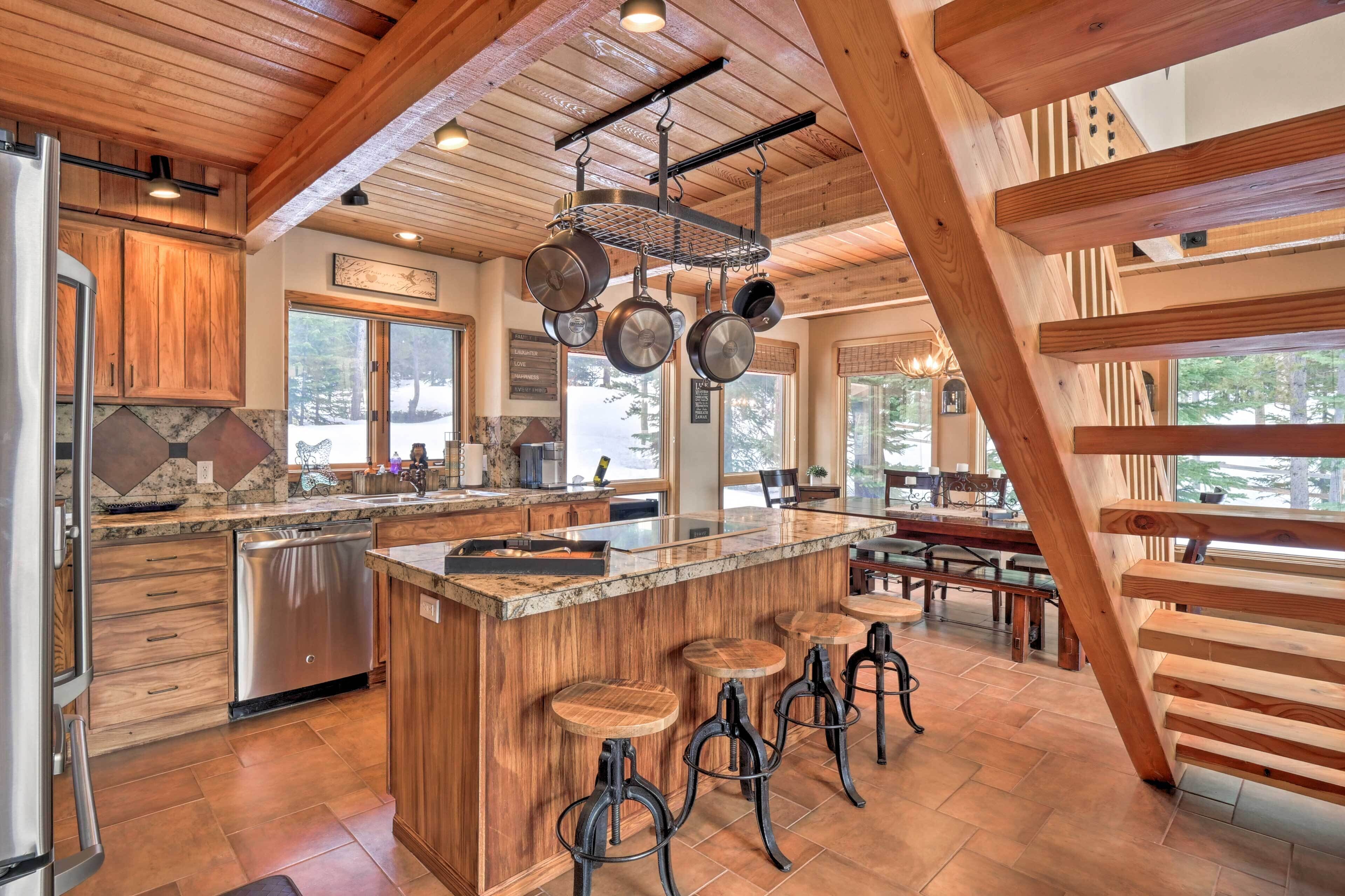 A spacious kitchen with wooden cabinets, a large island with stools, and a hanging pot rack.