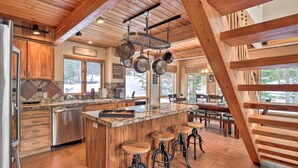 Una cocina amplia con armarios de madera, una isla grande con taburetes y una percha para ollas.
