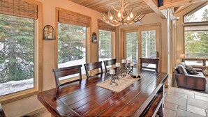 Un comedor con mesa de madera, sillas y una araña.