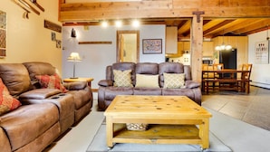 A cozy living room with a brown leather sofa, a wooden coffee table, and a dining area with a wooden table and chairs. - Silverthorne Condo W/pool Access - Shuttle to Town (Silverthorne)
