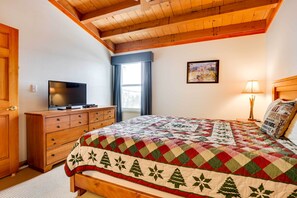 A bedroom with a large bed, wooden dresser, television, and a window with curtains. - Silverthorne Condo W/pool Access - Shuttle to Town (Silverthorne)