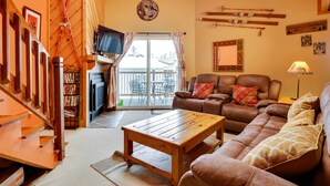 A cozy living room with a wooden coffee table, brown leather sofa, and a television. - Silverthorne Condo W/pool Access - Shuttle to Town (Silverthorne)