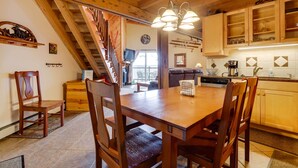 A wooden dining table with chairs, a kitchen with wooden cabinets, a staircase, and a view of the outside. - Silverthorne Condo W/pool Access - Shuttle to Town (Silverthorne)
