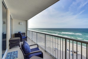 A balcony with wicker furniture and a view of the ocean.