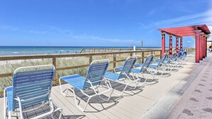 Une terrasse au bord de la plage, dotée de chaises longues et d’une pergola rouge.