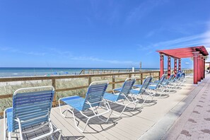 Una terrazza sulla spiaggia con lettini e un pergolato rosso.