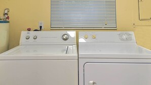Deux machines à laver à chargement frontal, superposées, dans une buanderie avec une fenêtre au-dessus.