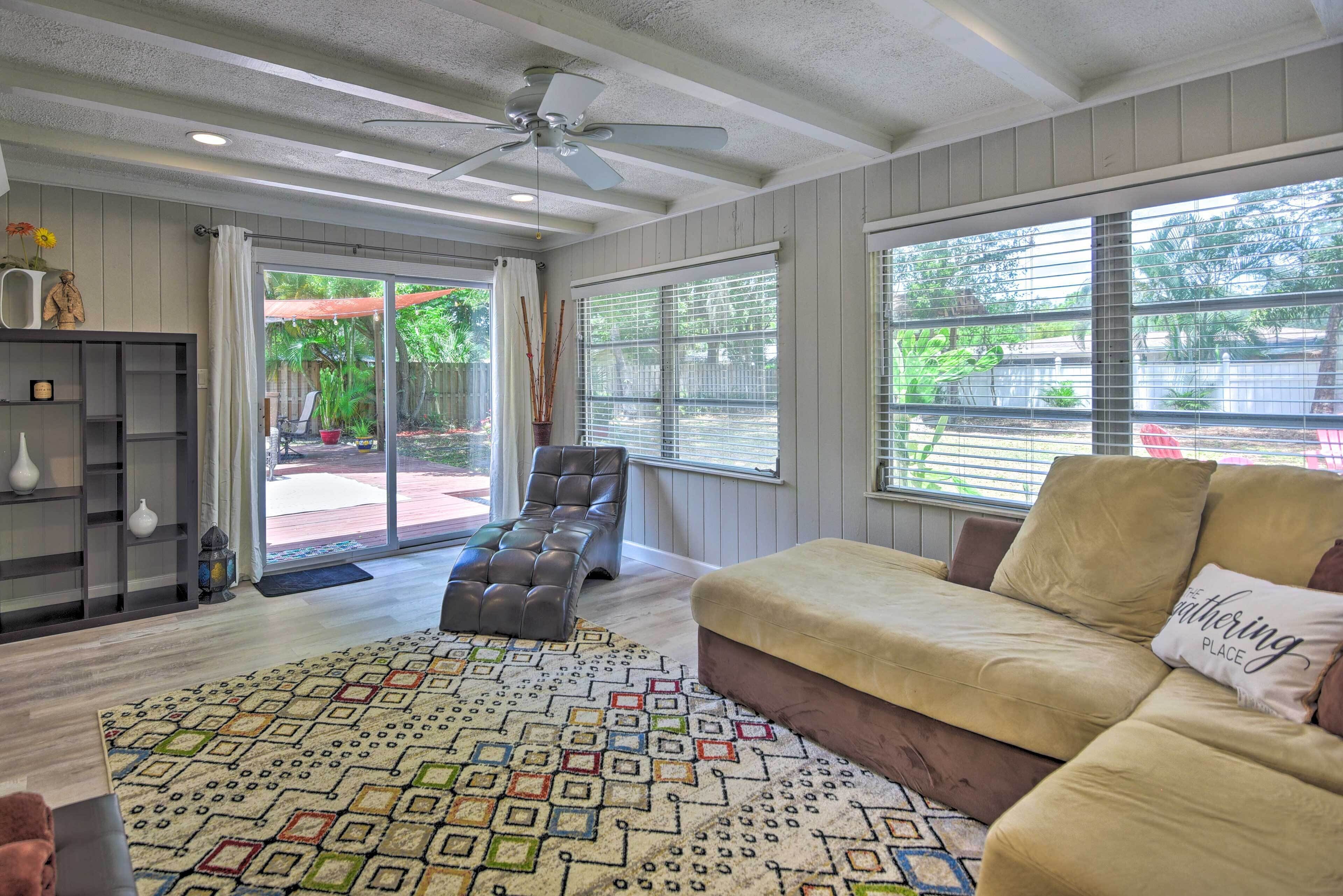A spacious living room with a beige sofa, a patterned rug, and a ceiling fan.