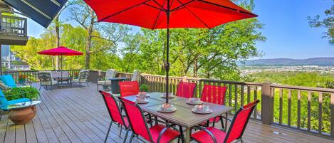 Une terrasse en bois avec une table et des chaises, des parasols rouges et une vue sur le paysage.