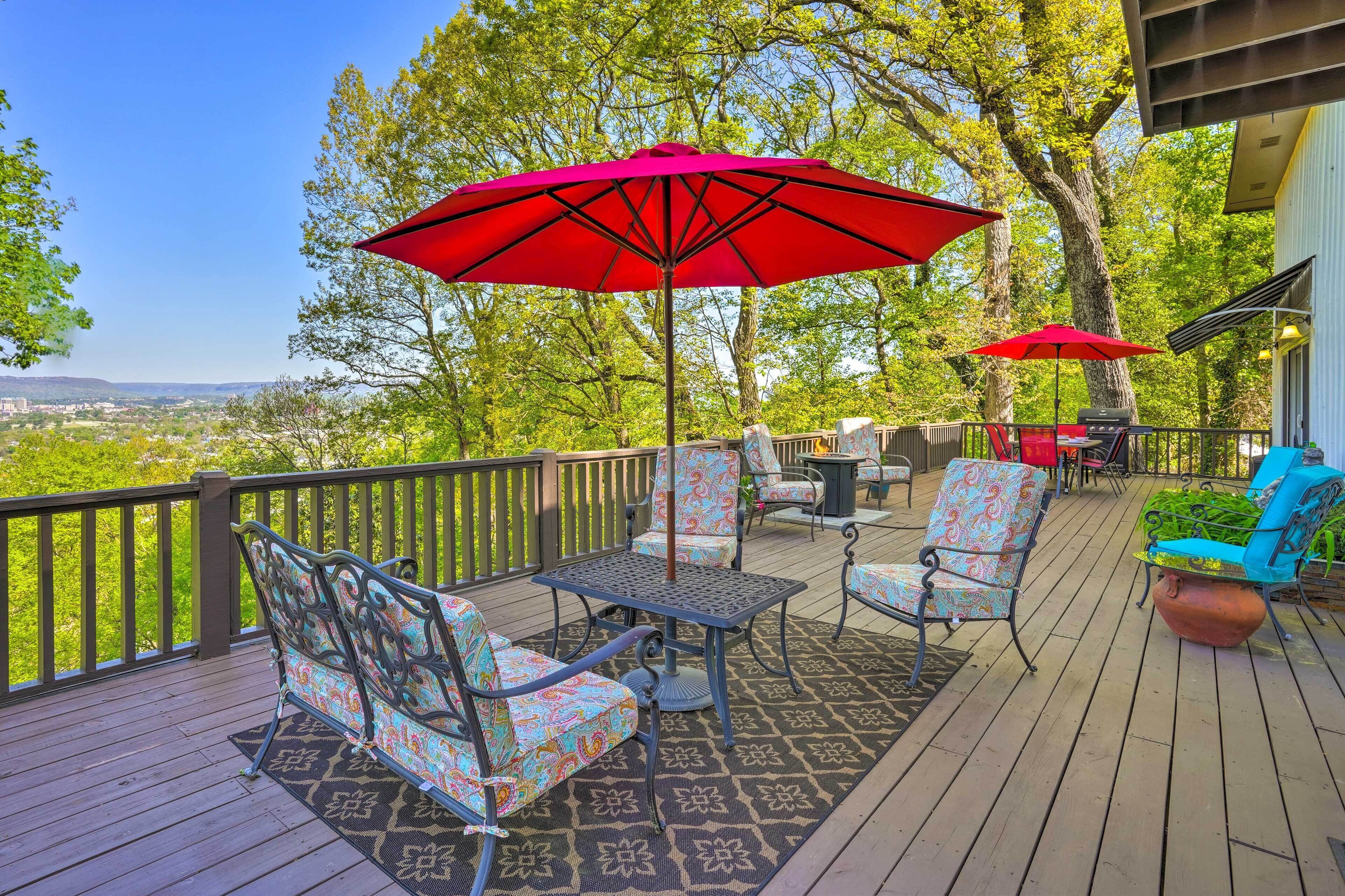 A deck with outdoor furniture, including chairs and a table, and two red umbrellas providing shade.