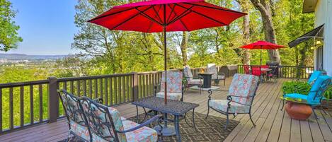 A deck with outdoor furniture, including chairs and a table, and two red umbrellas providing shade.
