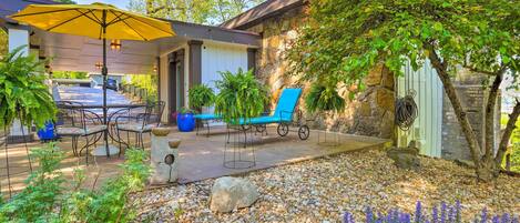 A patio area with outdoor furniture, a yellow umbrella, and a stone wall.