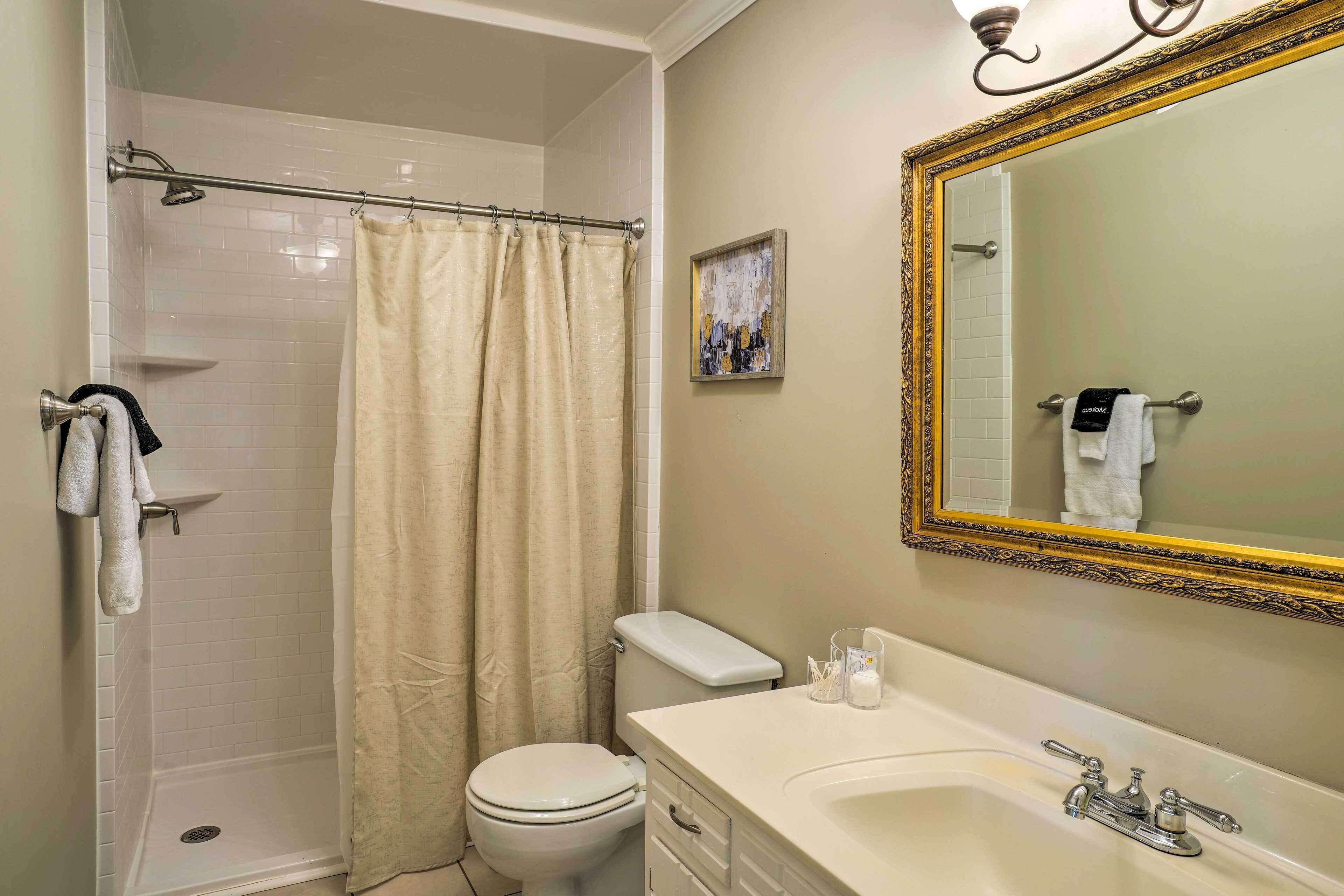 Une salle de bain équipée d’une douche, de toilettes, d’un lavabo et d’un grand miroir orné d’un cadre travaillé.